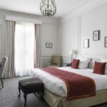 Chambre Double Privilège avec un grand lit et un bureau à l’Hôtel Bradford Elysées