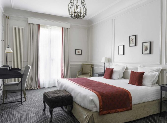 Chambre Double Privilège avec un grand lit et un bureau à l’Hôtel Bradford Elysées