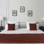 Chambre Double Privilège lit avec des draps blancs et des coussins rouges dans une chambre d’hôtel à l’Hôtel Bradford Elysées