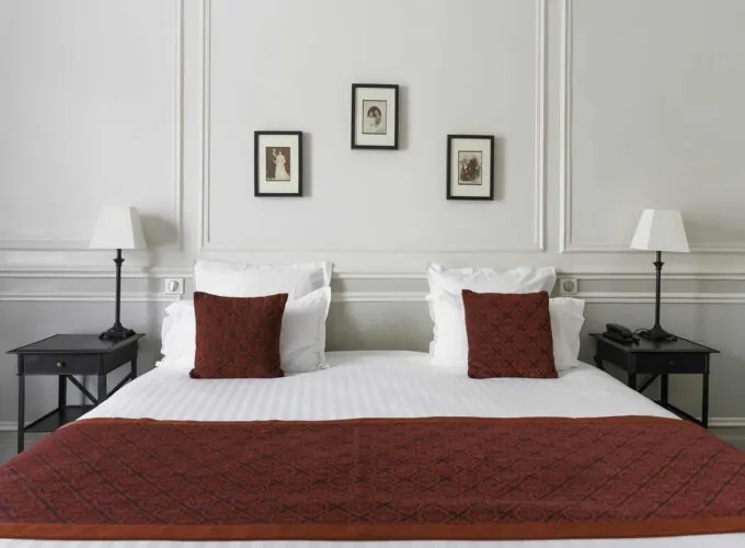 Chambre Double Privilège lit avec des draps blancs et des coussins rouges dans une chambre d’hôtel à l’Hôtel Bradford Elysées