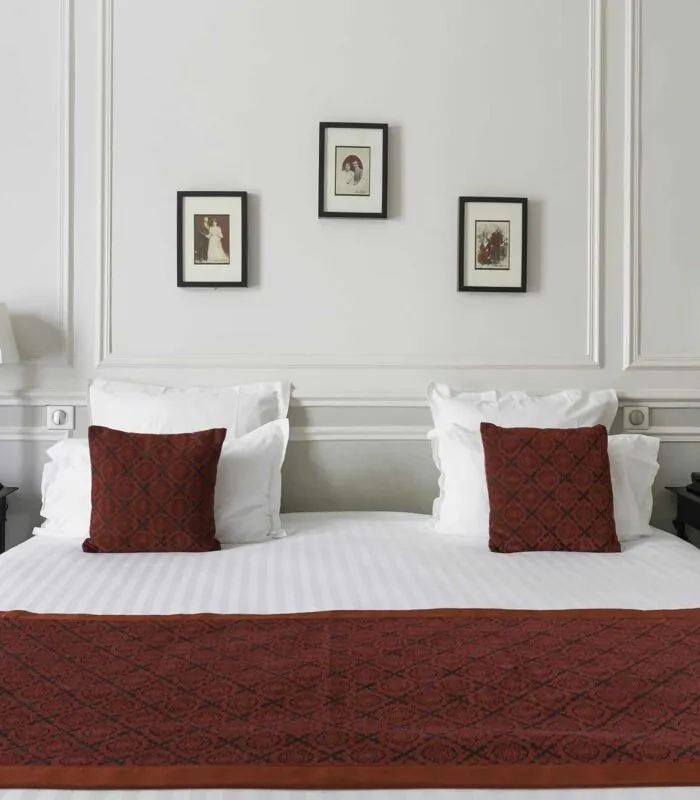 Chambre Double Privilège lit avec des draps blancs et des coussins rouges dans une chambre d’hôtel à l’Hôtel Bradford Elysées