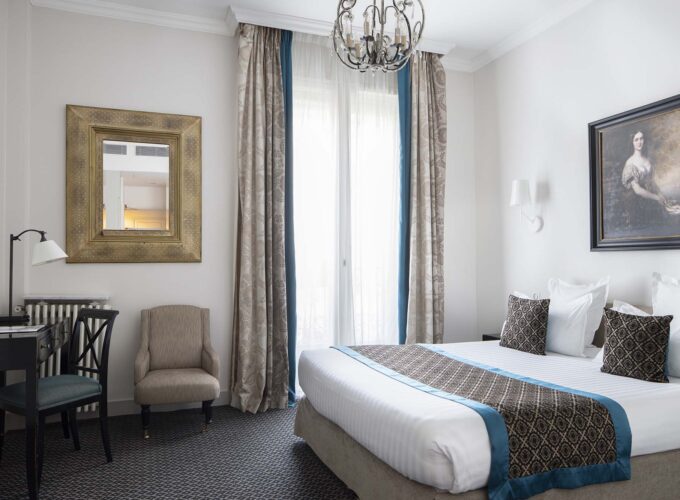 Chambre Double Supérieure avec un grand lit et un tableau accroché au mur à l’Hôtel Bradford Elysées