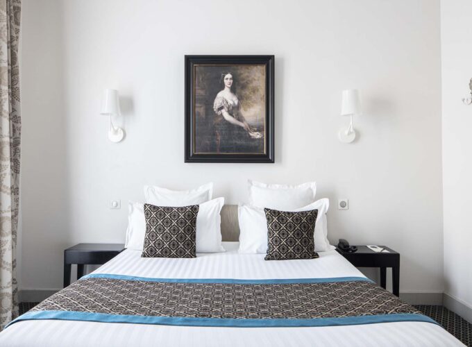 Chambre Double Supérieure – un tableau représentant une femme est accroché au-dessus d’un lit à l’Hôtel Bradford Elysées