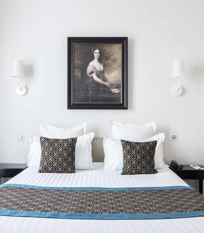 Chambre Double Supérieure – un tableau représentant une femme est accroché au-dessus d’un lit à l’Hôtel Bradford Elysées