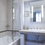 Chambre Double Supérieure salle de bain avec baignoire lavabo et miroir à l’Hôtel Bradford Elysées