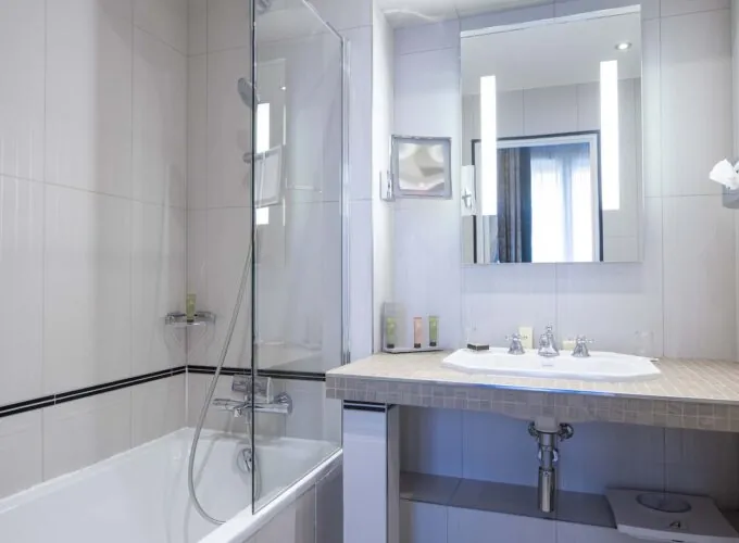 Chambre Double Supérieure salle de bain avec baignoire lavabo et miroir à l’Hôtel Bradford Elysées