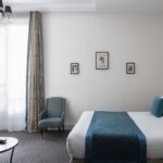 Chambre Familiale Supérieure avec un lit, une chaise et une télévision à écran plat à l’Hôtel Bradford Élysées