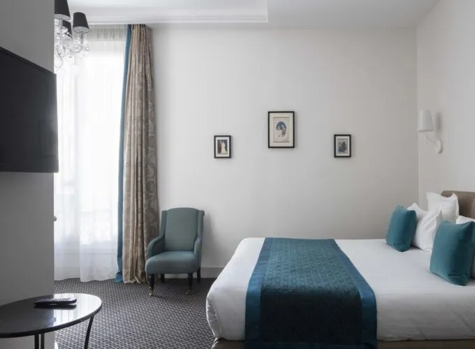 Chambre Familiale Supérieure avec un lit, une chaise et une télévision à écran plat à l’Hôtel Bradford Élysées