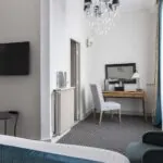 Chambre Familiale Supérieure avec un lit, une chaise et une télévision à écran plat à l’Hôtel Bradford Élysées