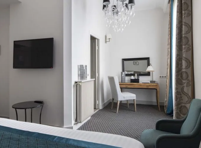 Chambre Familiale Supérieure avec un lit, une chaise et une télévision à écran plat à l’Hôtel Bradford Élysées