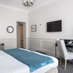 Chambre Familiale Supérieure avec un lit, un bureau et une télévision à écran plat à l’Hôtel Bradford Élysées