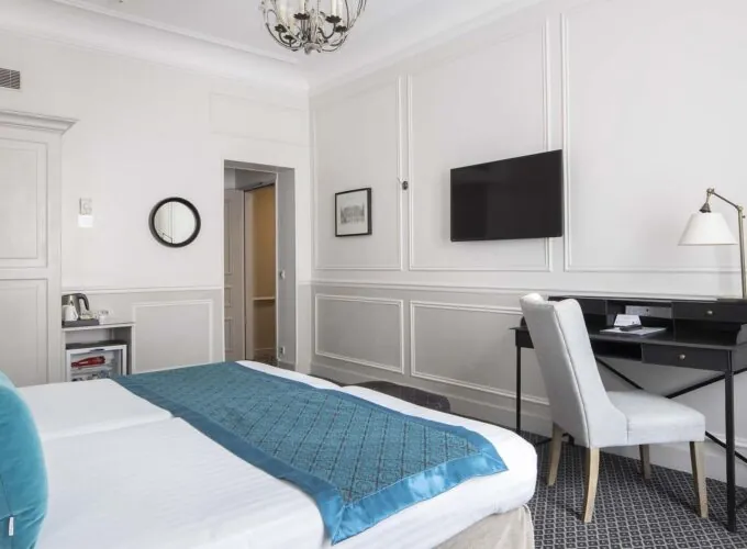 Chambre Familiale Supérieure avec un lit, un bureau et une télévision à écran plat à l’Hôtel Bradford Élysées