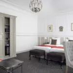 Chambre Privilège Balcon avec deux lits et un bureau à l’Hôtel Bradford Elysées