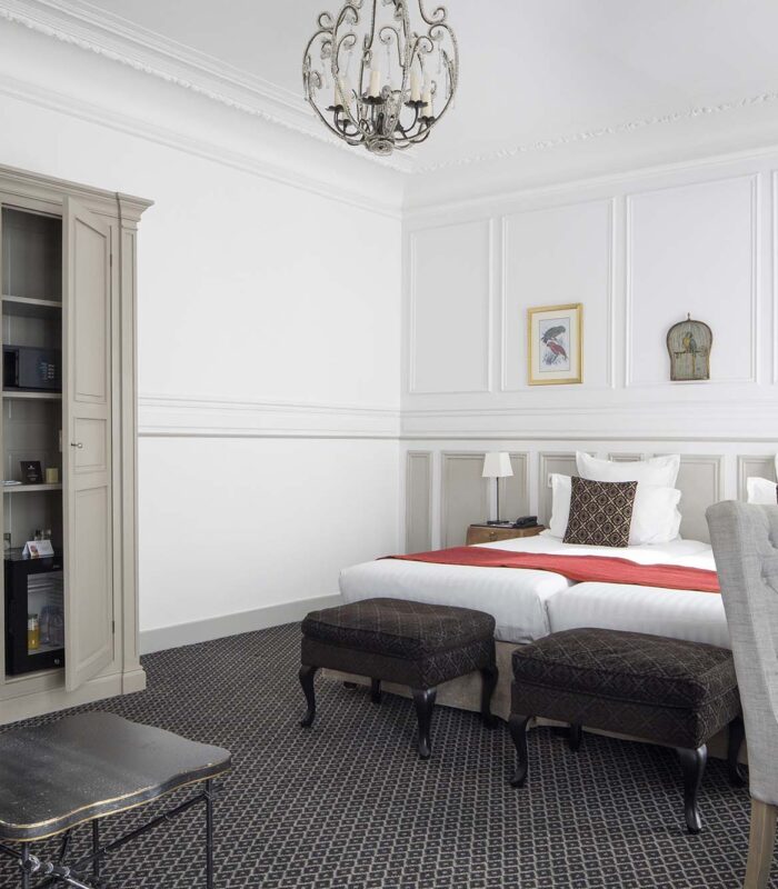 Chambre Privilège Balcon avec deux lits et un bureau à l’Hôtel Bradford Elysées