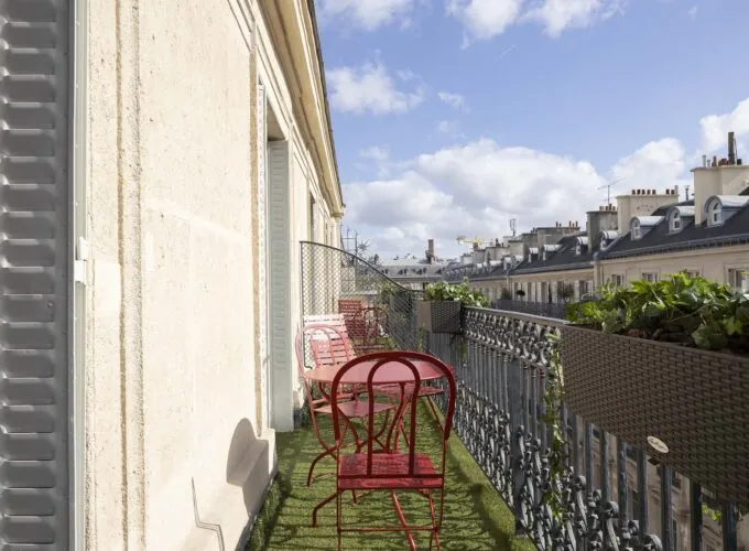 Chambre Privilège Balcon un balcon avec deux chaises rouges et une table à l’Hôtel Bradford Elysées