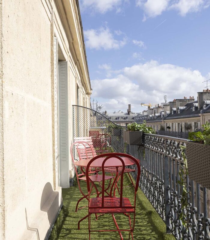Chambre Privilège Balcon un balcon avec deux chaises rouges et une table à l’Hôtel Bradford Elysées