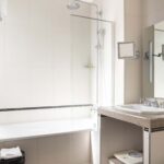 Chambre Privilège Balcon salle de bain avec une baignoire un lavabo et un miroir à l’Hôtel Bradford Elysées