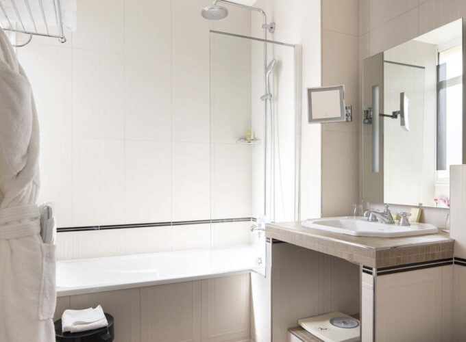 Chambre Privilège Balcon salle de bain avec une baignoire un lavabo et un miroir à l’Hôtel Bradford Elysées