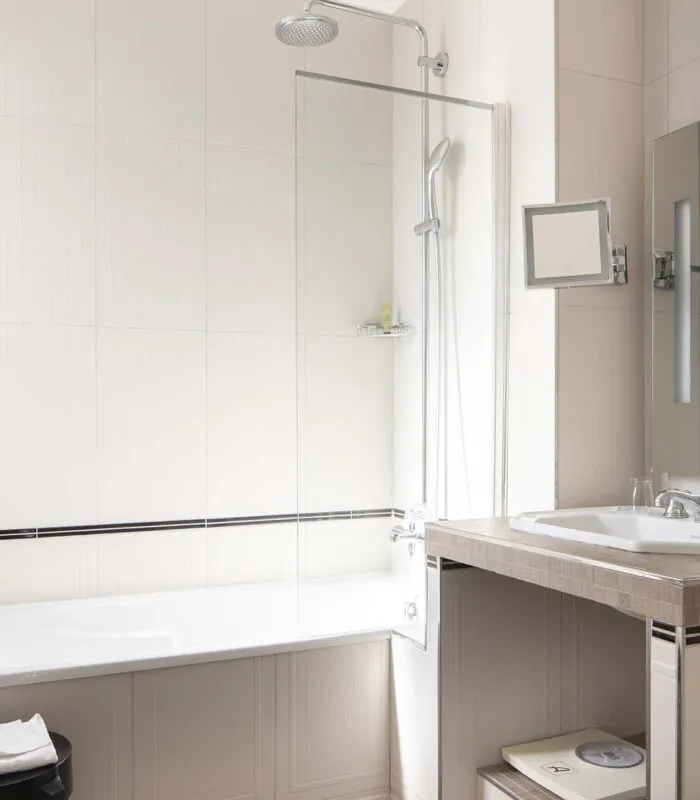 Chambre Privilège Balcon salle de bain avec une baignoire un lavabo et un miroir à l’Hôtel Bradford Elysées