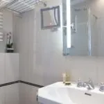Salle de bain de la chambre Single avec un lavabo, un miroir et une douche à l’hôtel Bradford Elysées