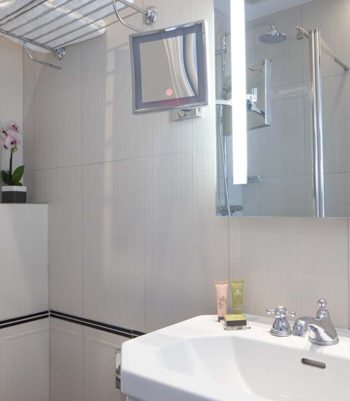 Salle de bain de la chambre Single avec un lavabo, un miroir et une douche à l’hôtel Bradford Elysées