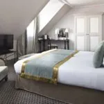 Chambre Triple Privilège avec un grand lit et une télévision à écran plat à l’Hôtel Bradford Elysées