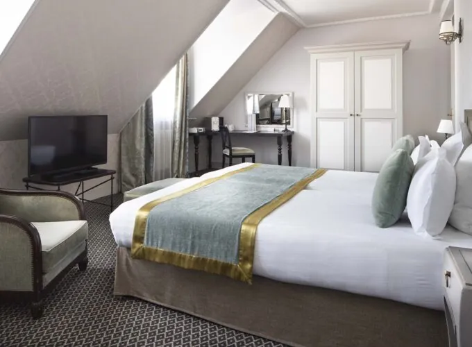 Chambre Triple Privilège avec un grand lit et une télévision à écran plat à l’Hôtel Bradford Elysées