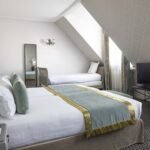 Chambre Triple Privilège avec deux lits et une télévision à écran plat à l’Hôtel Bradford Elysées