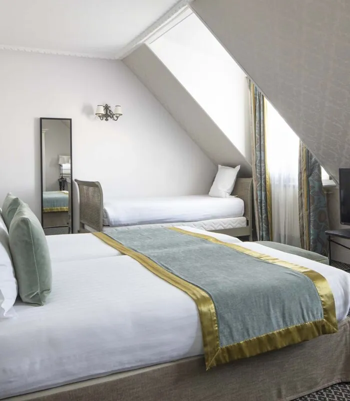 Chambre Triple Privilège avec deux lits et une télévision à écran plat à l’Hôtel Bradford Elysées