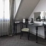 Chambre Triple Privilège avec un bureau une chaise et un miroir à l’Hôtel Bradford Elysées