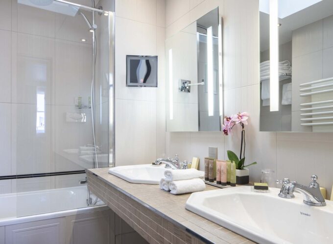 Chambre Triple Privilège salle de bain avec deux lavabos et une baignoire et le lavabo porte l’inscription Duravit à l’Hôtel Bradford Elysées