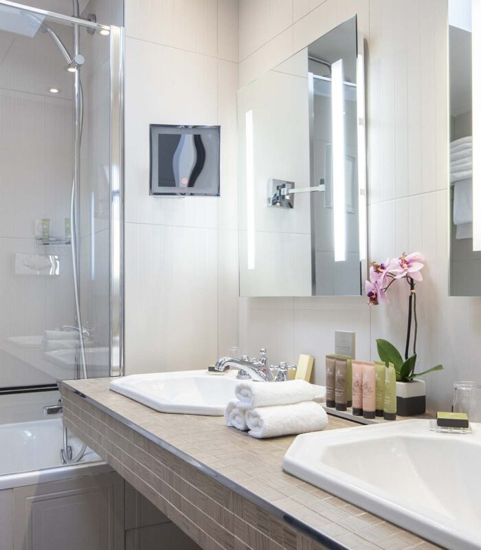 Chambre Triple Privilège salle de bain avec deux lavabos et une baignoire et le lavabo porte l’inscription Duravit à l’Hôtel Bradford Elysées
