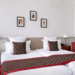 Chambre Twin avec deux lits et trois tableaux encadrés au mur à l’Hôtel Bradford Élysées