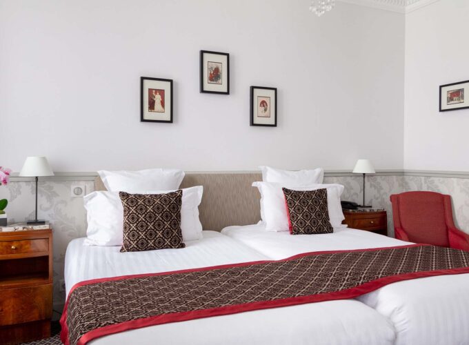 Chambre Twin avec deux lits et trois tableaux encadrés au mur à l’Hôtel Bradford Élysées