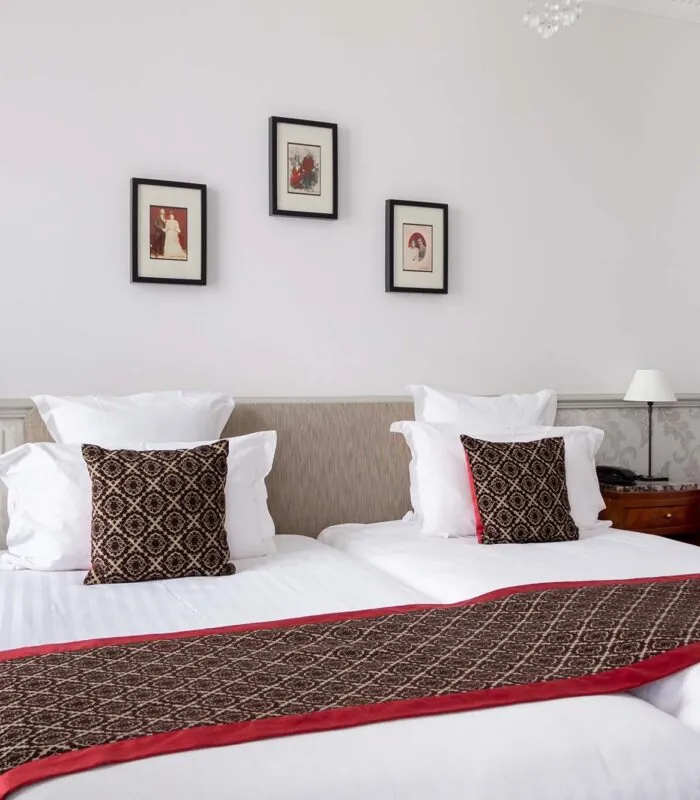 Chambre Twin avec deux lits et trois tableaux encadrés au mur à l’Hôtel Bradford Élysées