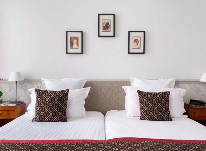 Chambre Twin avec deux lits et trois tableaux encadrés au mur à l’Hôtel Bradford Élysées