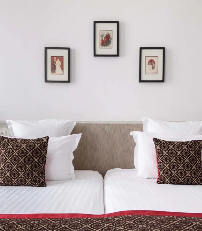 Chambre Twin avec deux lits et trois tableaux encadrés au mur à l’Hôtel Bradford Élysées