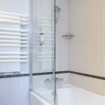 Salle de bain Twin avec une baignoire et un porte-serviettes à l’Hôtel Bradford Élysées