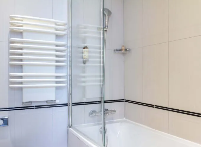 Salle de bain Twin avec une baignoire et un porte-serviettes à l’Hôtel Bradford Élysées