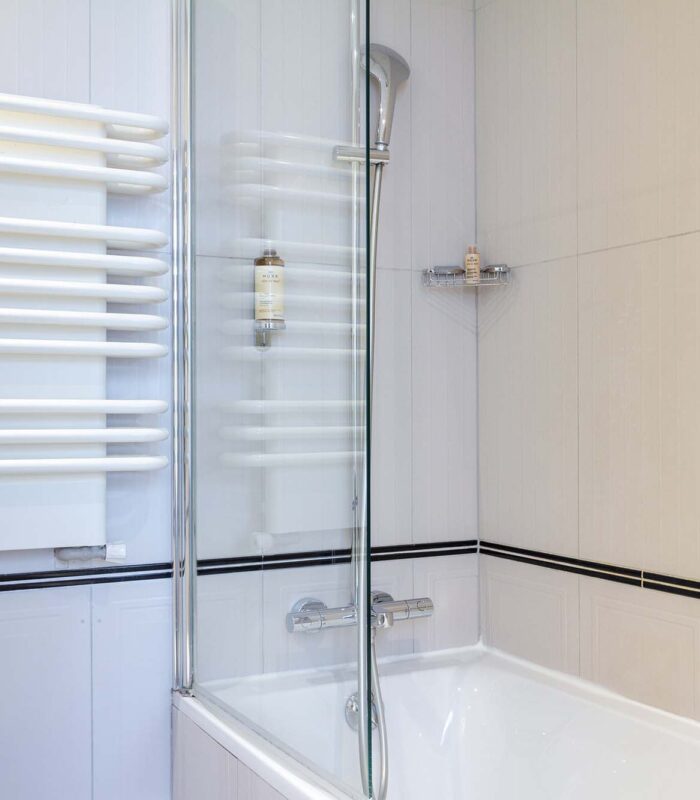 Salle de bain Twin avec une baignoire et un porte-serviettes à l’Hôtel Bradford Élysées