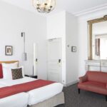 Chambre Twin Supérieure avec deux lits et une chaise rouge à l’Hôtel Bradford Élysées
