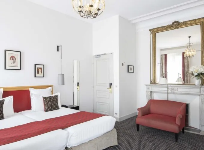 Chambre Twin Supérieure avec deux lits et une chaise rouge à l’Hôtel Bradford Élysées