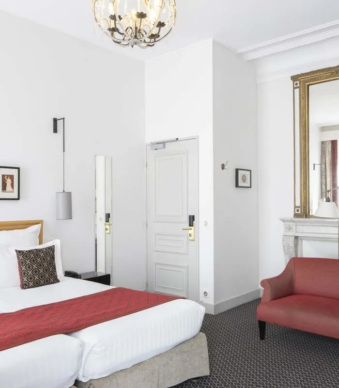 Chambre Twin Supérieure avec deux lits et une chaise rouge à l’Hôtel Bradford Élysées