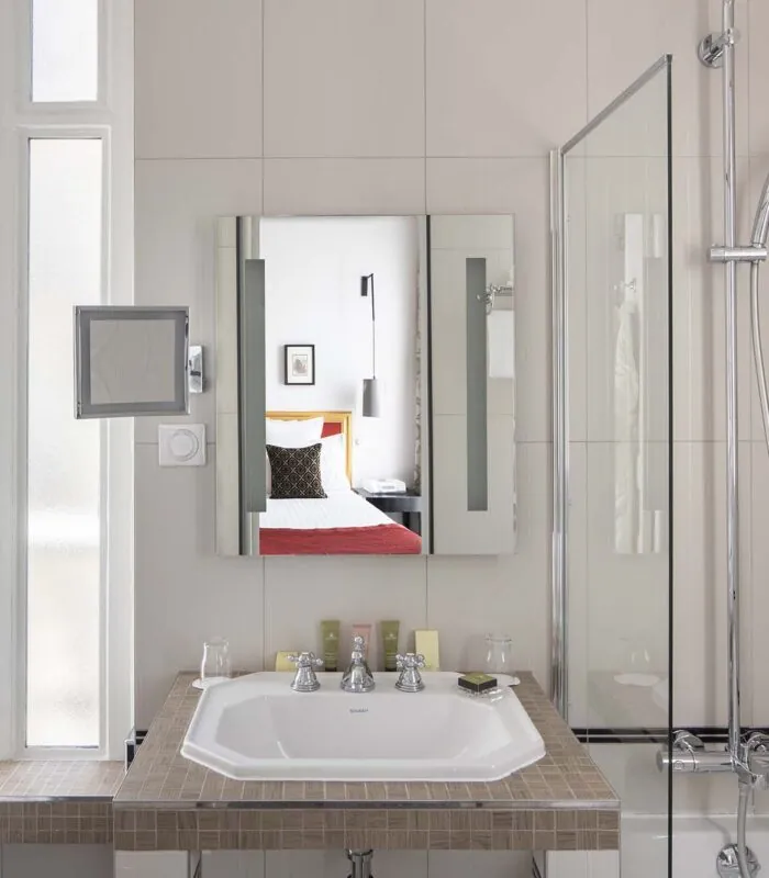 Salle de bain Twin Supérieure avec un lavabo, un miroir et une douche à l’Hôtel Bradford Élysées