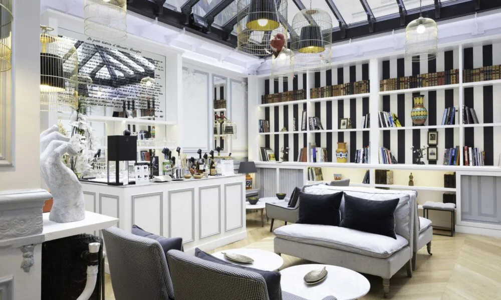 Bar élégant de l’Hôtel Bradford Elysées à Paris avec des étagères modernes, des fauteuils confortables et des luminaires distinctifs