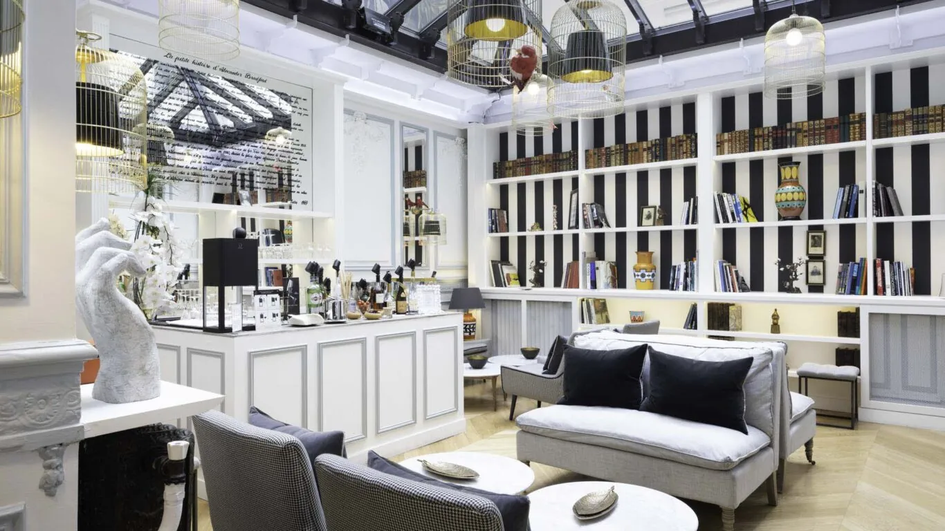 Bar élégant de l’Hôtel Bradford Elysées à Paris avec des étagères modernes, des fauteuils confortables et des luminaires distinctifs