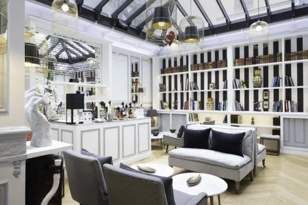 Bar élégant de l’Hôtel Bradford Elysées à Paris avec des étagères modernes, des fauteuils confortables et des luminaires distinctifs