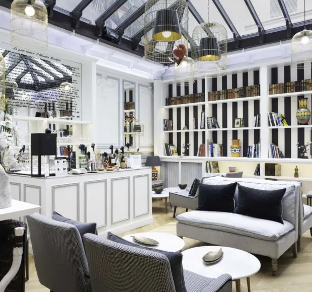 Bar élégant de l’Hôtel Bradford Elysées à Paris avec des étagères modernes, des fauteuils confortables et des luminaires distinctifs