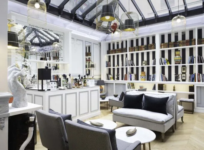 Bar élégant de l’Hôtel Bradford Elysées à Paris avec des étagères modernes, des fauteuils confortables et des luminaires distinctifs