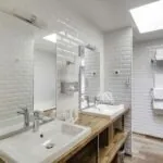 Appartement salle de bain avec deux lavabos et deux miroirs à l’hôtel George